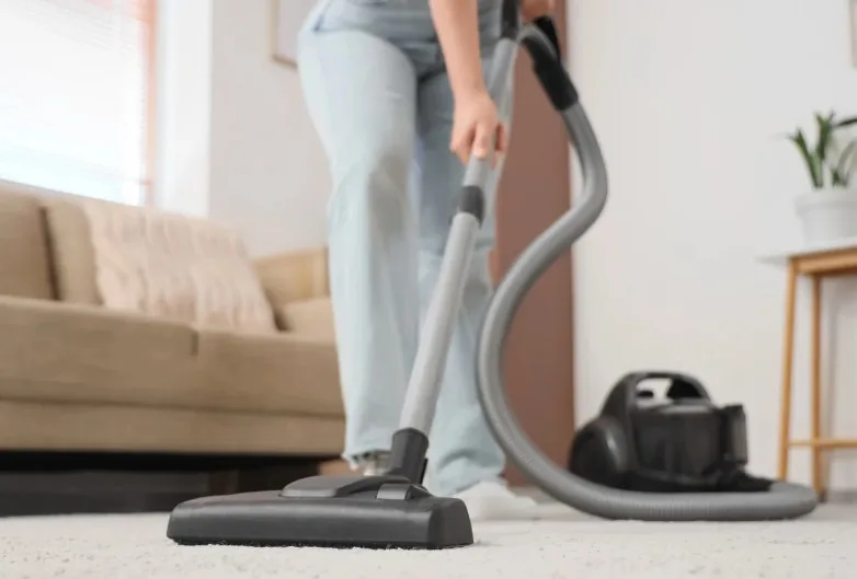Operaria aspirando la moqueta del salón de un apartamento con aspirador profesional