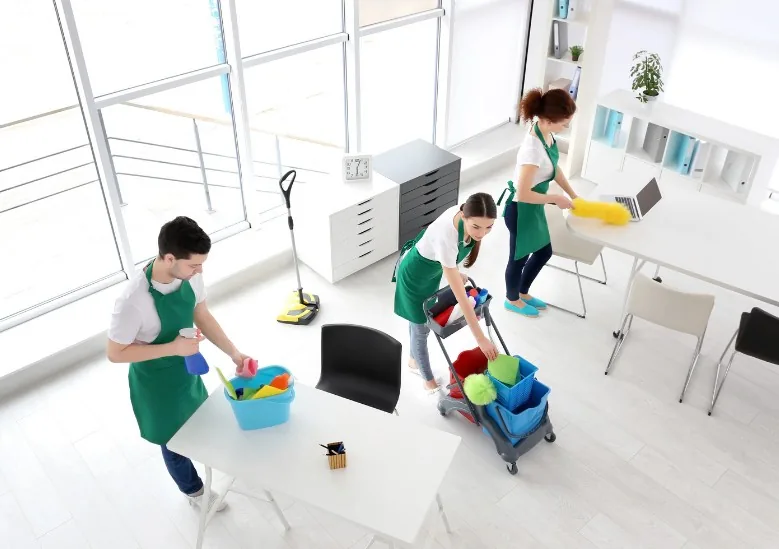 Equipo de limpieza de tres personas trabajando en una oficina diáfana